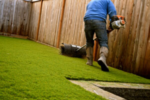 workers,installing,artificial,turf,in,a,residential,yard.